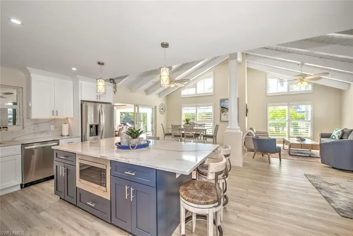 Kitchen with ceiling fan, white cabinetry, hanging light fixtures, stainless steel appliances, and a kitchen island
