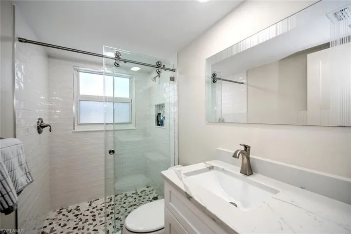 Bathroom featuring vanity, an enclosed shower, and toilet