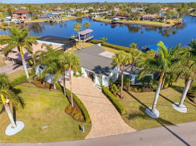 Aerial view of property featuring a water view, lush land scaping