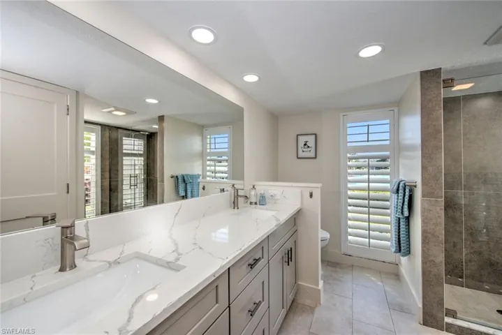 Bathroom with a tile shower, vanity, tile patterned floors, and toilet
