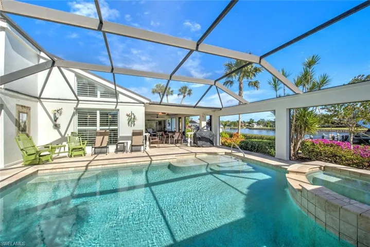 View of swimming pool with an in ground hot tub, a water view, glass enclosure, and a patio