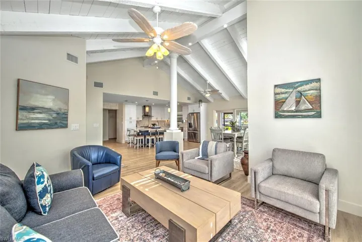 Living room with hardwood / wood-style flooring, beamed ceiling, high vaulted ceiling, and ceiling fan