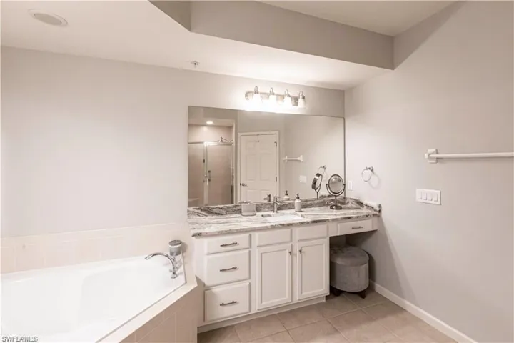 Full bath with vanity, a garden tub, light tile patterned flooring, and a shower stall