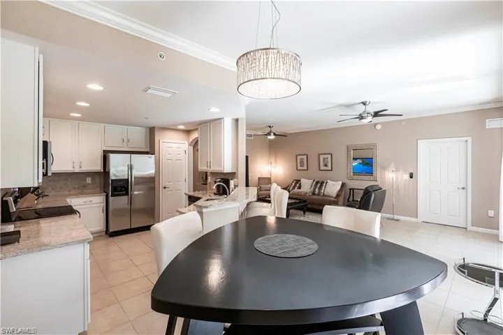 Dining room with crown molding, light tile patterned flooring, a ceiling fan, and suspended lighting