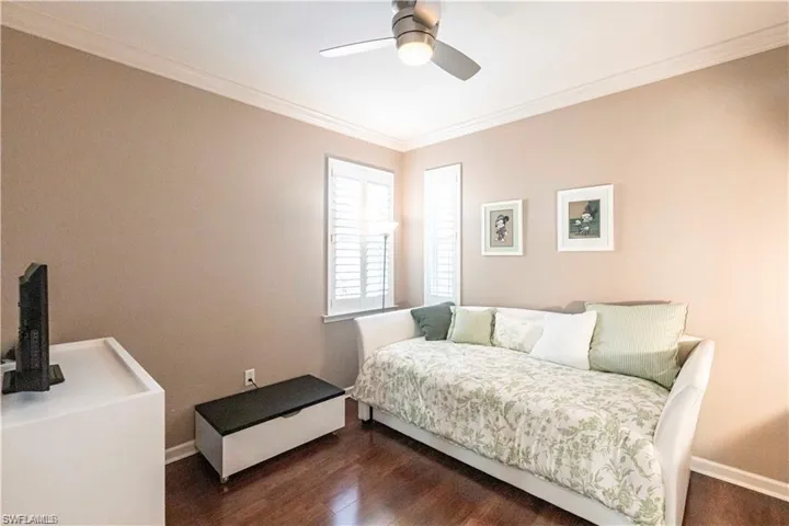 Bedroom featuring ornamental molding, dark wood-style flooring, and ceiling fan