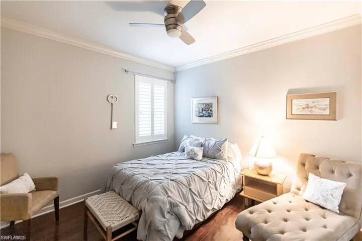 Bedroom with crown molding, wood finished floors, and a ceiling fan