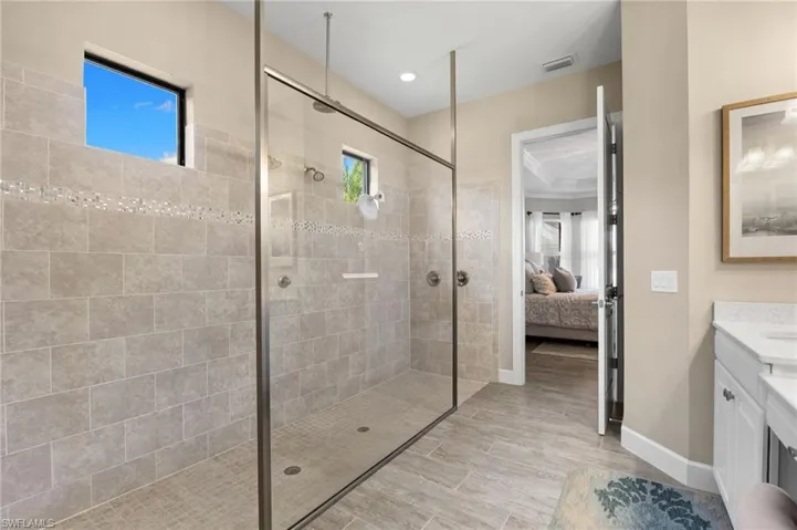 Ensuite bathroom with vanity, healthy amount of natural light, and a walk in shower