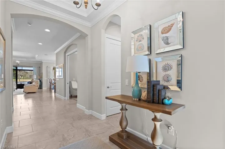 Hall featuring arched walkways, ornamental molding, and a chandelier