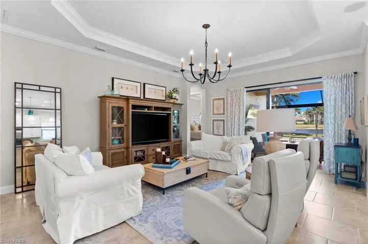Living room featuring hanging lights, ornamental molding, and a tray ceiling