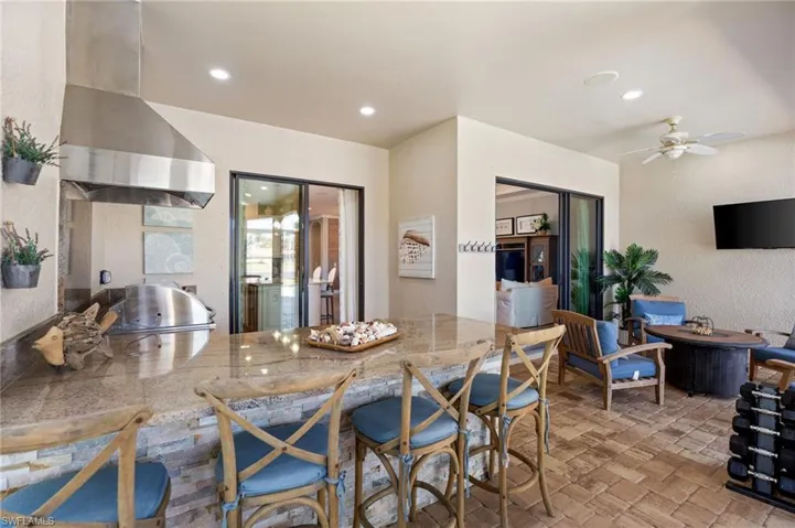 Kitchen featuring a textured wall, ceiling fan, light stone countertops, recessed lighting, and brick patterned floors