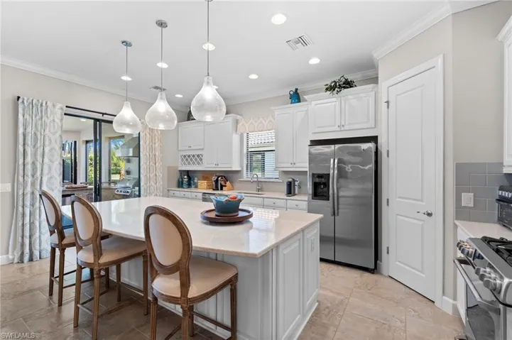 Kitchen with white cabinetry, a kitchen bar, stainless steel appliances, tasteful backsplash, and a center island