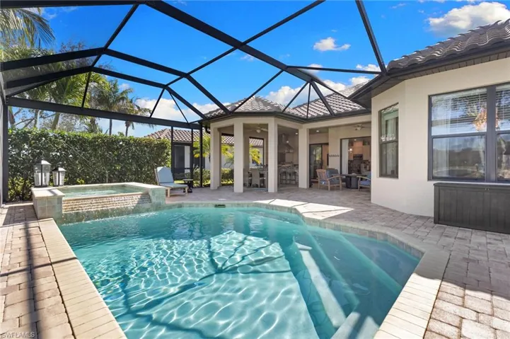 Relaxing pool / spa with a patio, a sunroom, a lanai, and outdoor dining area