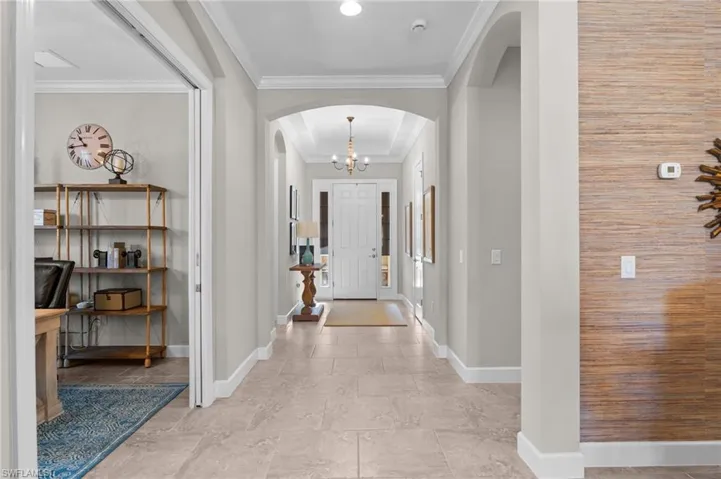 Entryway with arched walkways, crown molding, and suspended lighting