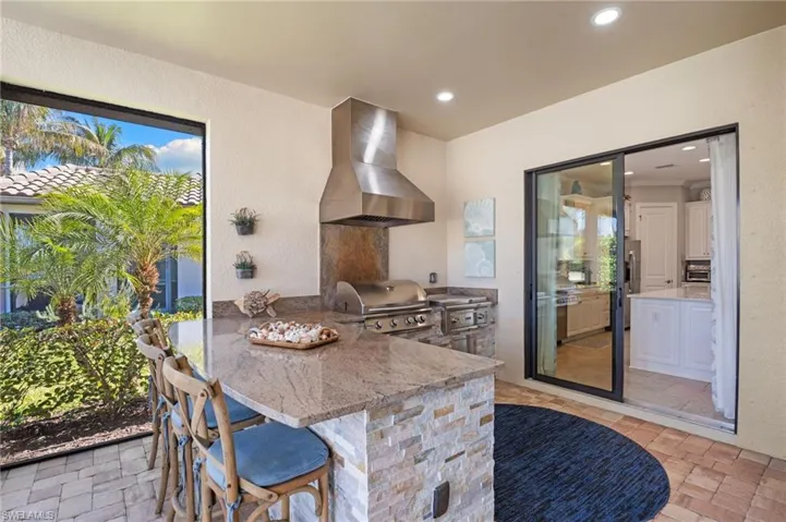 Kitchen featuring a breakfast bar area, a textured wall, a peninsula, light stone countertops, and recessed lighting
