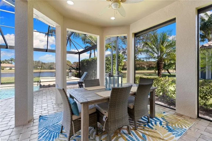 Sunroom / solarium with ceiling fan, a patio, outdoor dining area, and a water view