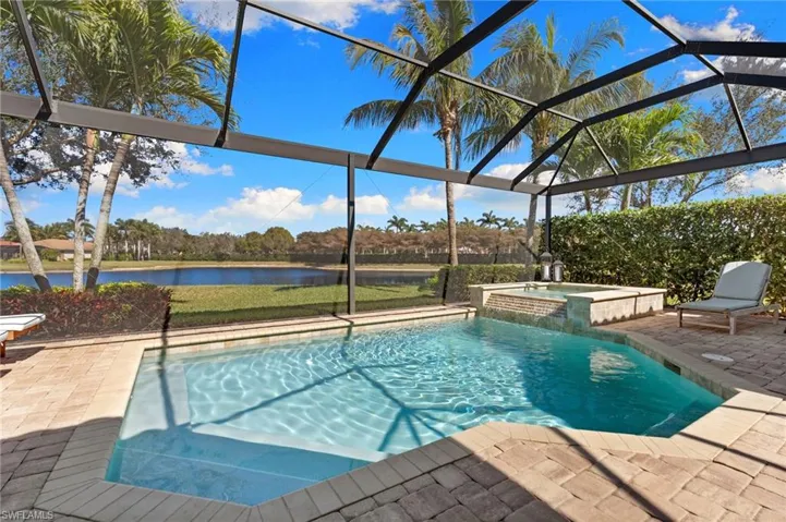 Combined pool / hot tub with a lanai, a water view, a sunroom, and a patio