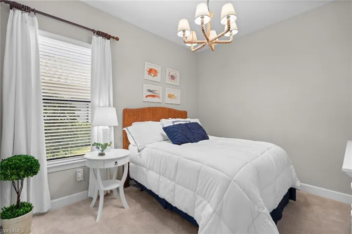 Bedroom with hanging lights and light carpet