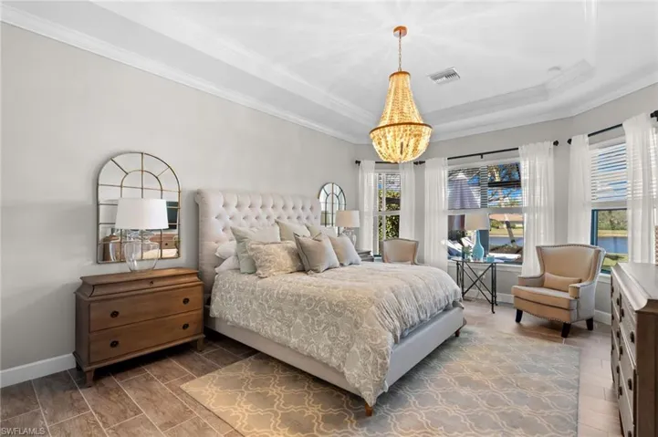 Bedroom featuring wood tiled floors, ornamental molding, and a tray ceiling