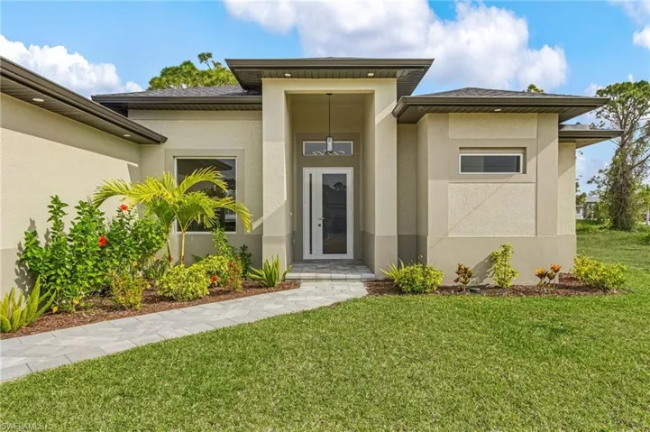 Doorway to property with a yard and stucco siding