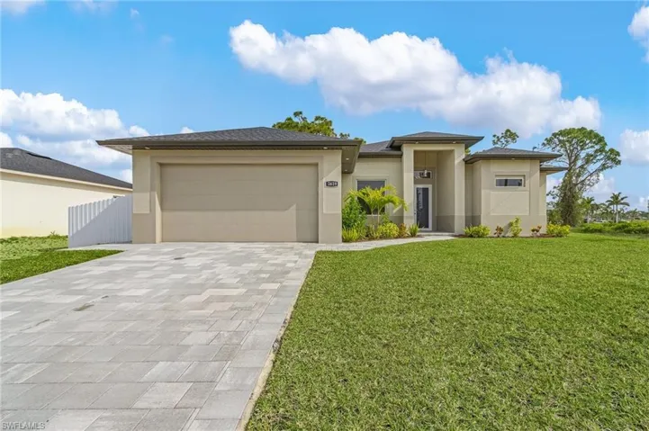 Prairie-style home featuring decorative driveway, stucco siding, a front lawn, and an attached garage