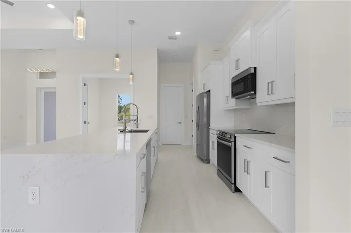 Kitchen with white cabinetry, appliances with stainless steel finishes, light stone countertops, pendant lighting, and recessed lighting