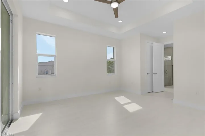Spare room featuring a tray ceiling, recessed lighting, ceiling fan, and light wood-type flooring