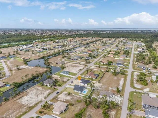 Aerial view of property and surrounding area featuring a nearby body of water and nearby suburban area