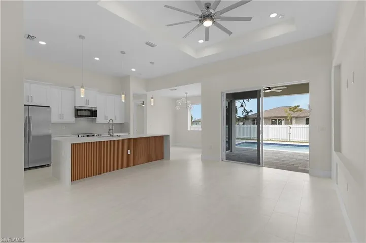 Kitchen with ceiling fan, appliances with stainless steel finishes, open floor plan, a spacious island, and white cabinets