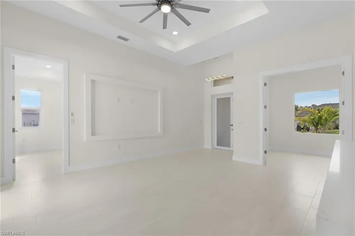 Empty room featuring a raised ceiling, ceiling fan, light wood-type flooring, and recessed lighting