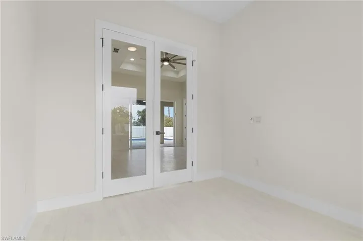 Empty room featuring french doors, light wood-type flooring, and recessed lighting