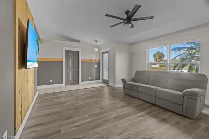 Living area featuring lofted ceiling, wood finished floors, ceiling fan, and baseboards