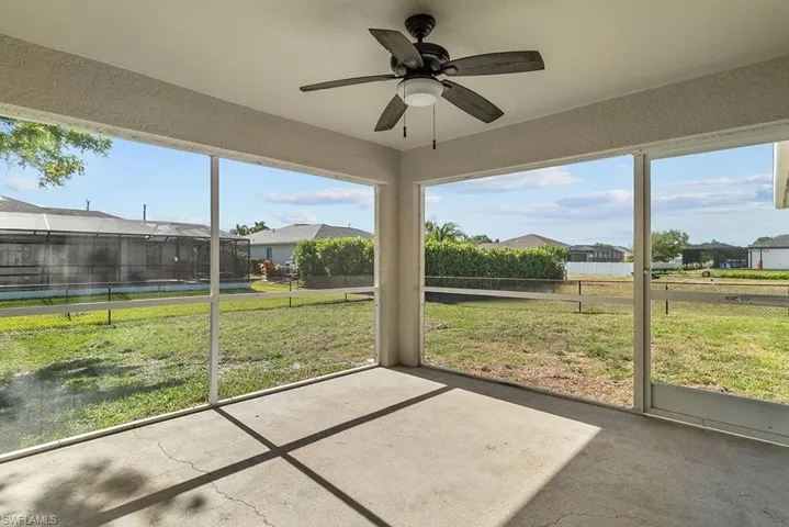 Unfurnished sunroom with a ceiling fan and a residential view