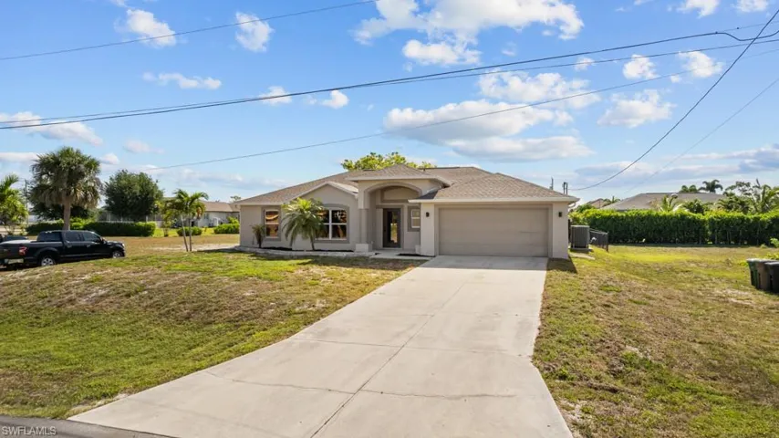 Single story home with an attached garage, stucco siding, concrete driveway, and a front lawn