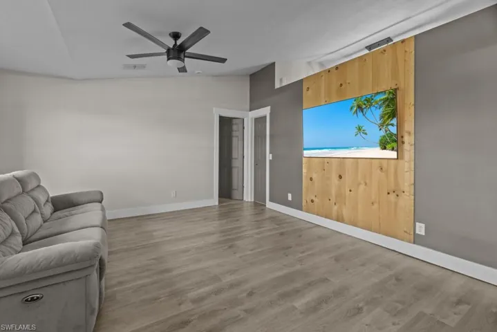 Living room with lofted ceiling, a ceiling fan, wood finished floors, and baseboards