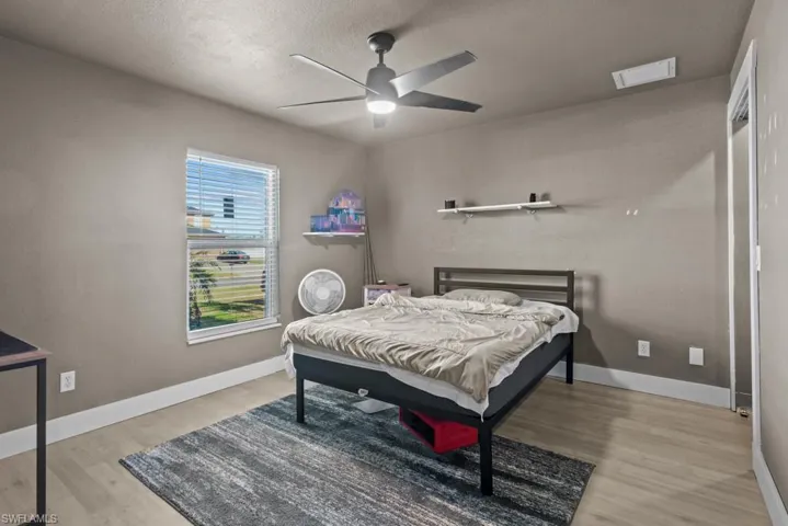 Bedroom featuring wood finished floors, a textured ceiling, baseboards, and ceiling fan