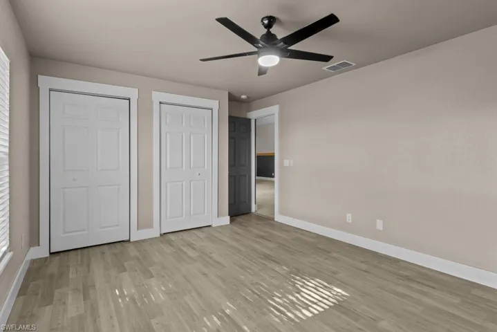 Unfurnished bedroom with baseboards, two closets, and light wood-type flooring