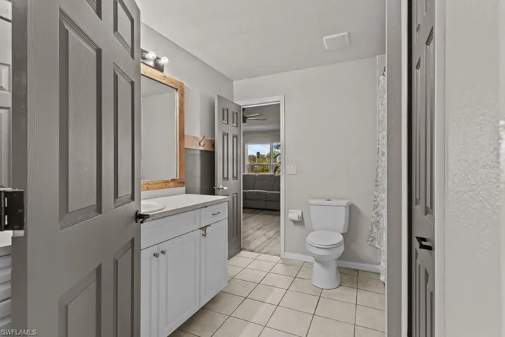 Full bath with toilet, vanity, tile patterned flooring, a textured ceiling, and baseboards