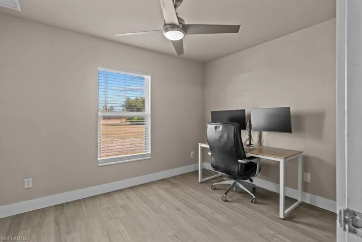 Office area featuring light wood-style flooring, ceiling fan, and baseboards