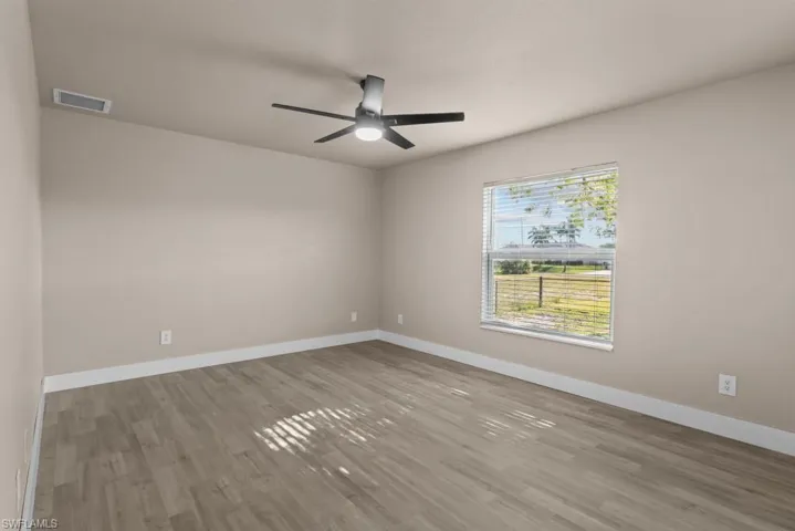 Spare room featuring wood finished floors, baseboards, and ceiling fan