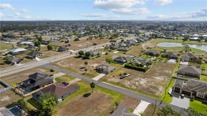Aerial view of property and surrounding area featuring a nearby body of water, nearby suburban area, and a local golf course