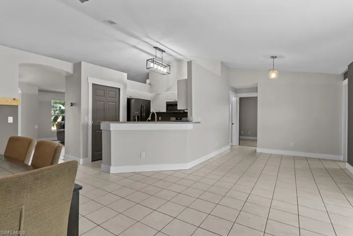 Living room with lofted ceiling, light tile patterned floors, arched walkways, and baseboards