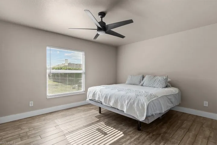 Bedroom with wood finished floors, baseboards, and ceiling fan