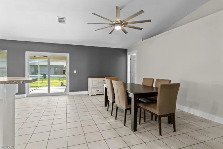 Dining area featuring vaulted ceiling, a ceiling fan, and light tile patterned flooring