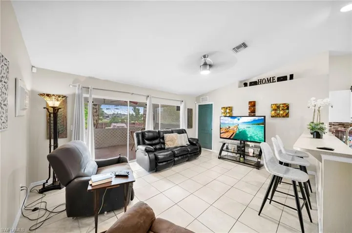 Living room featuring ceiling fan, lofted ceiling, and light tile patterned floors