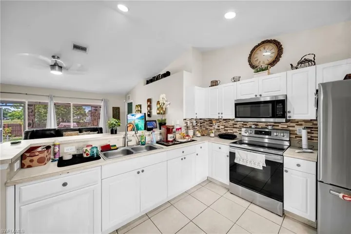 Kitchen with kitchen peninsula, sink, ceiling fan, appliances with stainless steel finishes, and white cabinetry