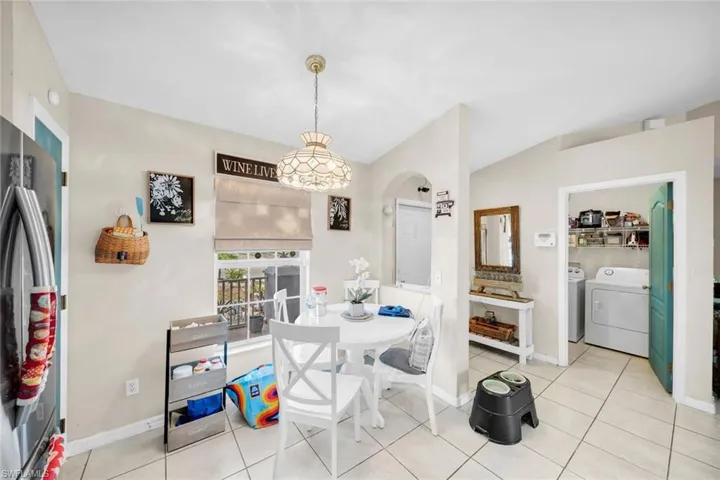 Dining space with light tile patterned floors, separate washer and dryer, and vaulted ceiling