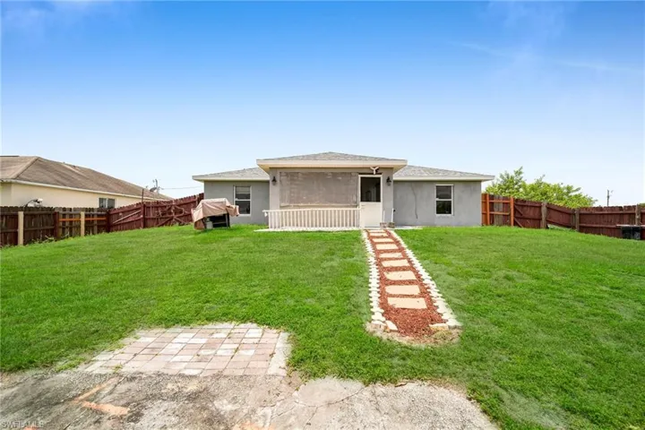 Rear view of house featuring a sunroom and a lawn