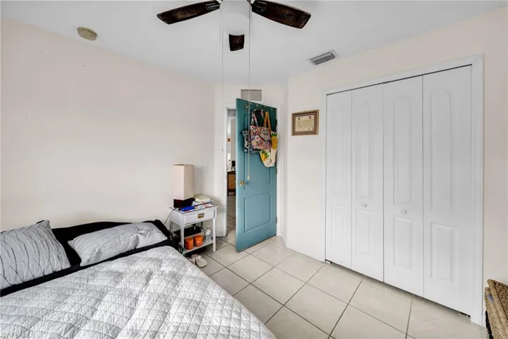Tiled bedroom with ceiling fan and a closet