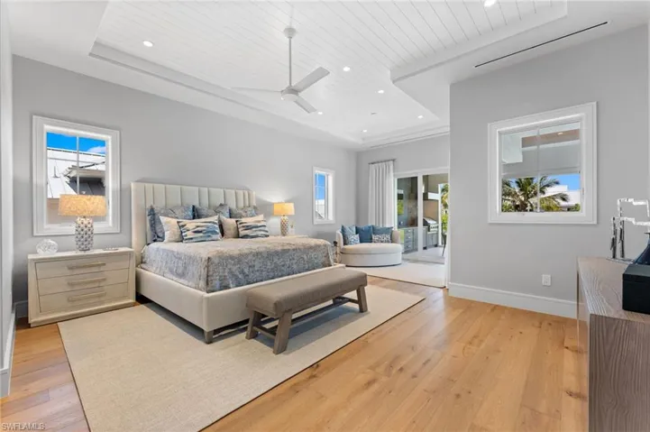 Bedroom with wood ceiling, a raised ceiling, recessed lighting, light wood finished floors, and multiple windows