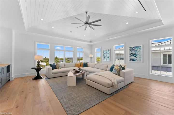 Living room with a raised ceiling, healthy amount of natural light, wooden ceiling, and recessed lighting
